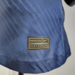 Close-up of blue woven fabric with a black-and-yellow rectangular patch that reads 'ENGINEERED' and a serial code beneath it.