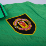 Close-up of a Manchester United crest embroidered on a bright green jersey.