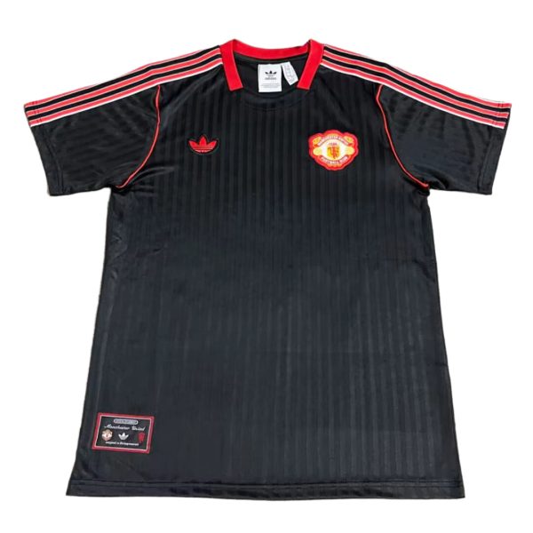 Black Manchester United football jersey with red shoulder stripes and club crest on the chest.