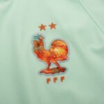 Mint green fabric featuring an orange embroidered rooster badge with two small stars above and 'FFF' lettering below.