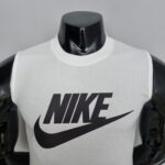 White Nike tank top on a glossy black mannequin torso with a large black swoosh across the chest.
