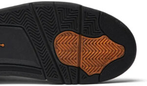 Bottom view of a black sneaker sole with an orange tread patch for traction detail.