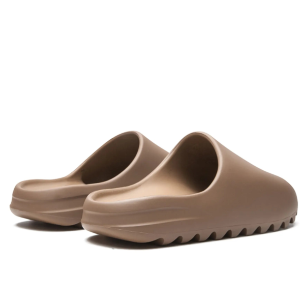 Pair of taupe slide sandals with sculpted wavy uppers and thick ridged soles.