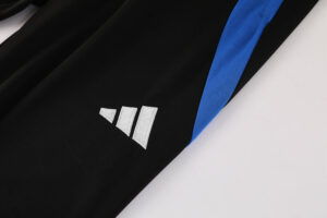 Close-up of black sports fabric with white embroidered three-stripe logo and blue piping