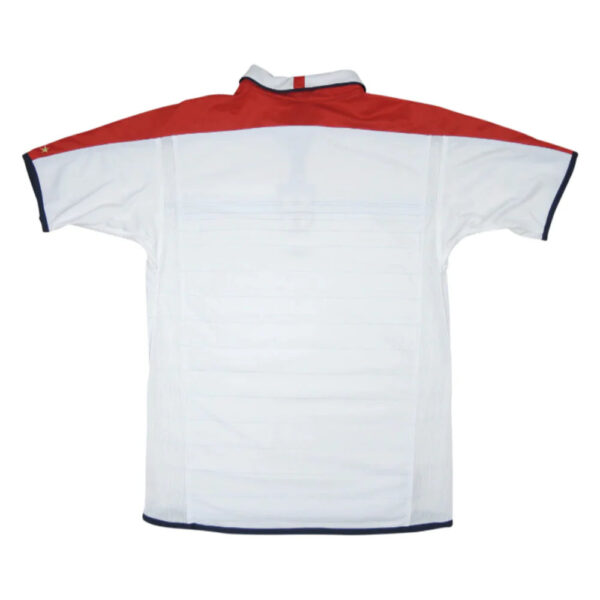 Back view of a white polo shirt with a red yoke, navy sleeve trim, and small star detail on the left sleeve.
