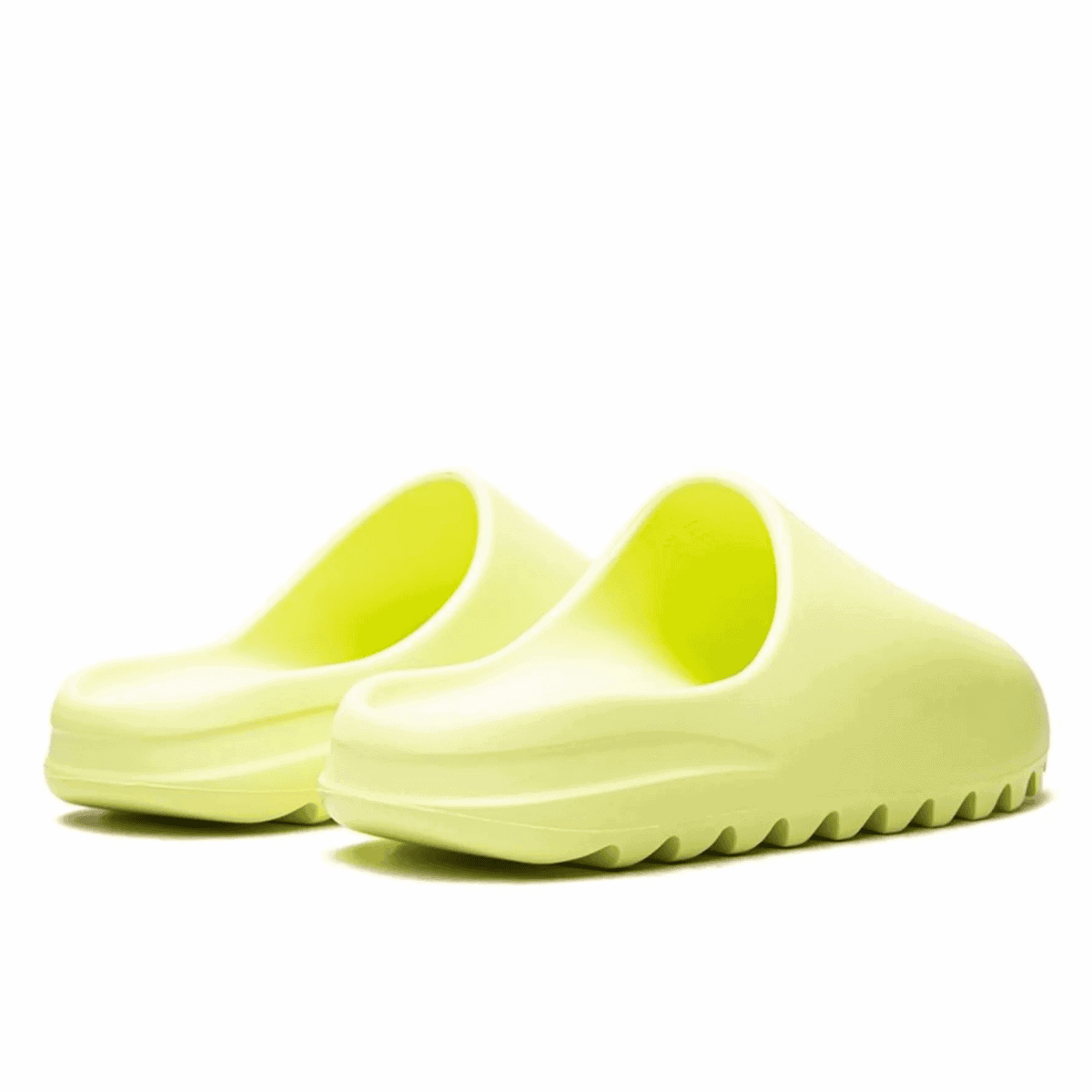 Close-up of lime-green slip-on sandals with wide, curved straps on a white background.
