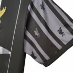 Close-up of a black blazer sleeve with gray striped lining featuring small black Liverbird logos.
