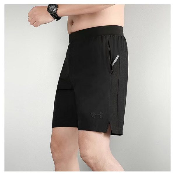 Model wearing black athletic shorts with a zippered side pocket and a small Under Armour logo, shown in a side view.