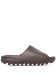 Close-up of a brown clog-style shoe showing a large serrated, wave-like outsole.