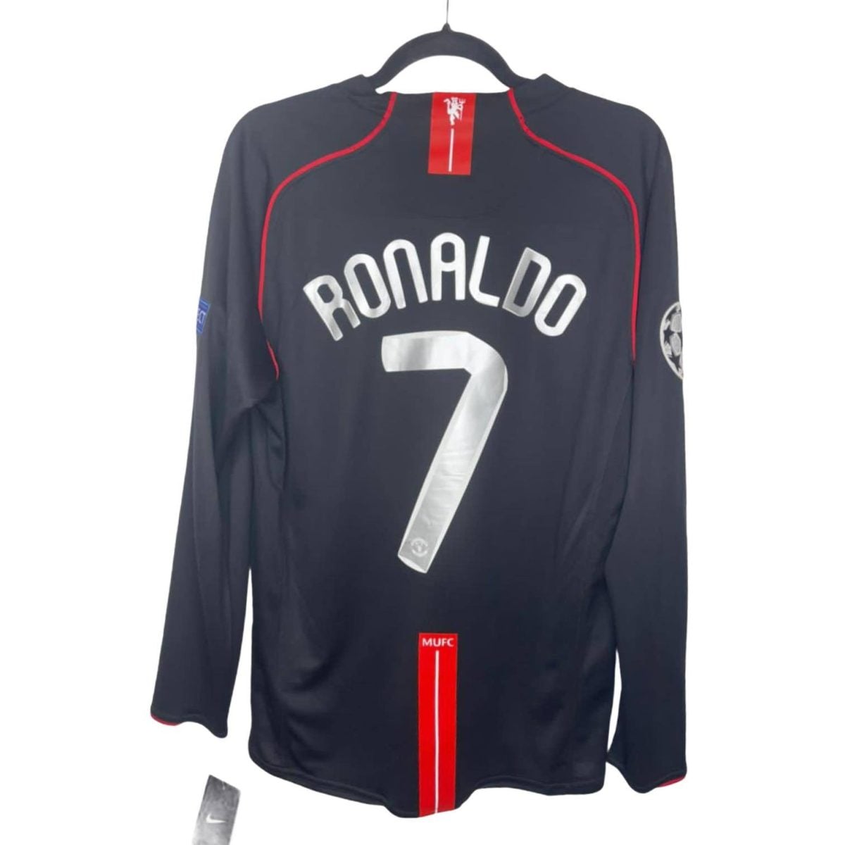 Dark blue Manchester United Ronaldo jersey with red piping, number 7 on back, hanging on a hanger.