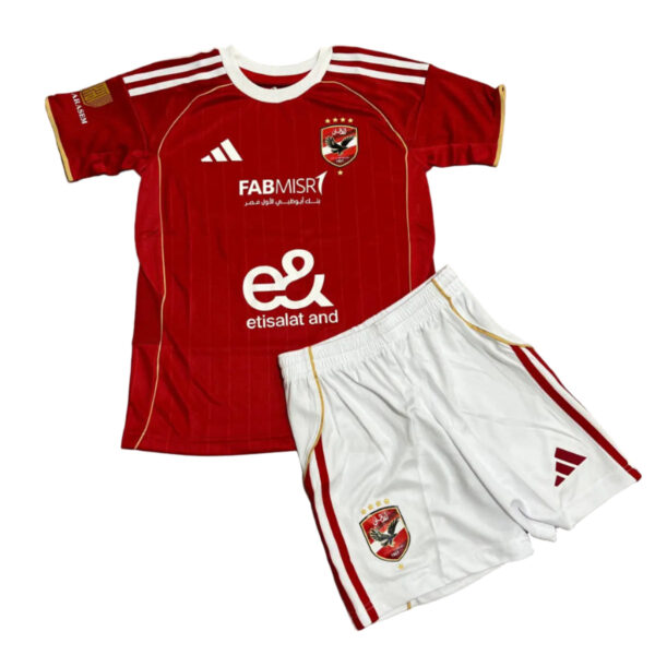 Red soccer kit with white pinstripes and white collar, crest on the chest, and sponsor logos, paired with white shorts with red side stripes.