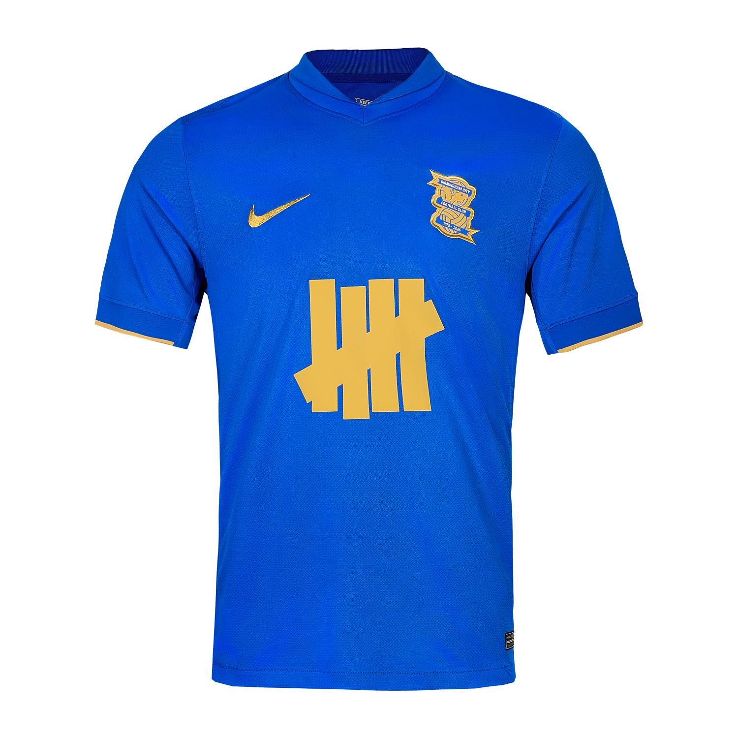 1767-930 | UAE SPORT STORE Blue Birmingham City FC football jersey with a gold Nike swoosh on the right and the club crest on the left, featuring a large gold tally-mark graphic across the chest.