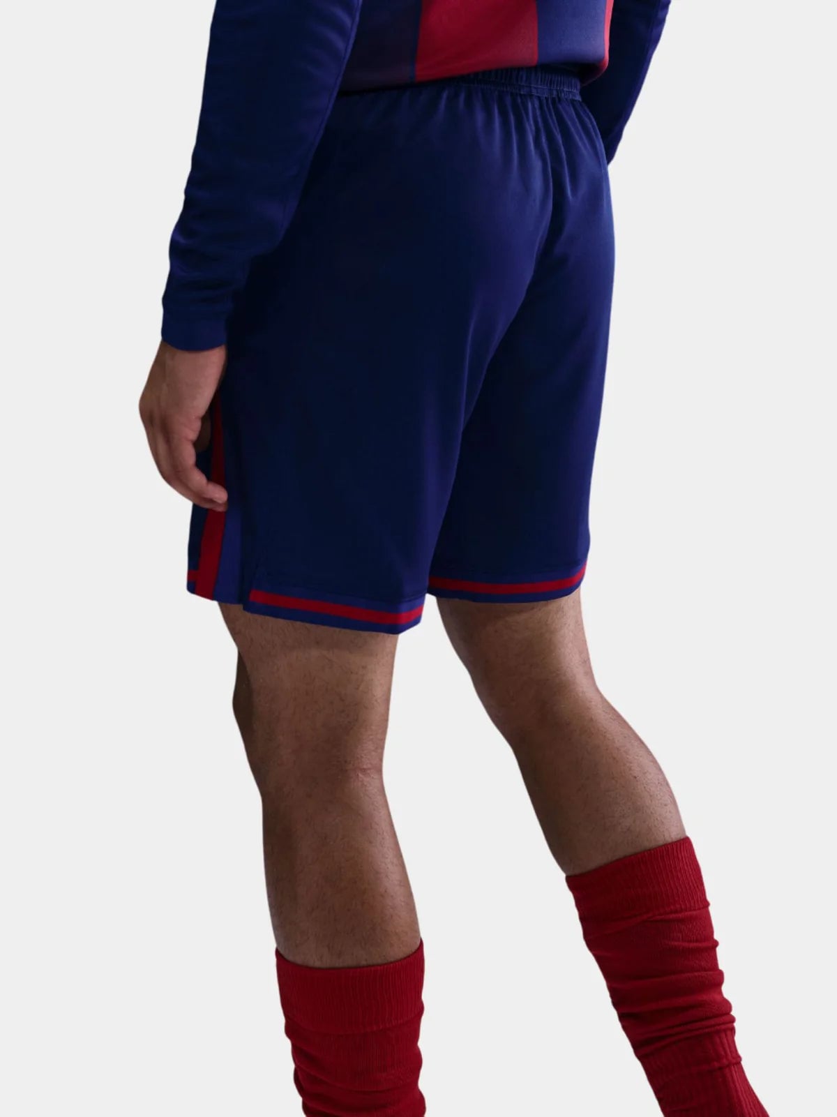 18 | UAE SPORT STORE Back view of a person wearing navy blue athletic shorts with red piping along the edges and matching red socks.