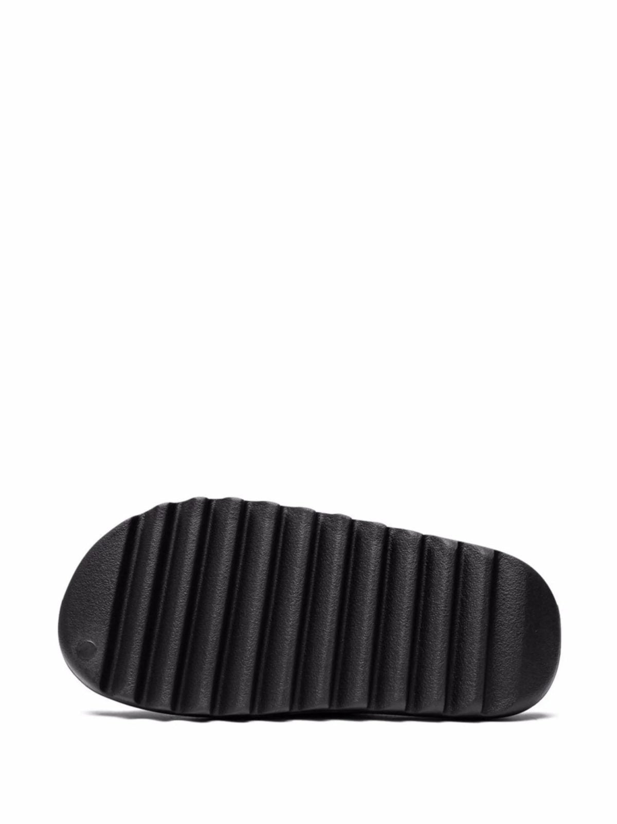 Close-up of a black rubber sandal strap with vertical ridges on a white background