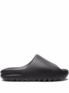 Black slip-on sandal with a textured strap and grooved sole, shown from the side on a white background.