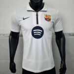 White FC Barcelona polo jersey on a black mannequin, with Nike logo on the chest, club crest on the right, and a Spotify sponsor circle in the center.