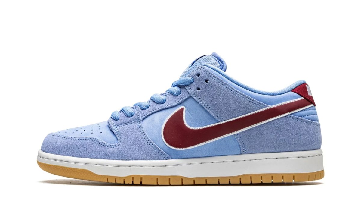 Blue suede sneaker with a red side swoosh, shown from a side angle on a white background.