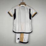 Back view of a white Adidas soccer jersey hanging on a wooden hanger, with black and gold trim and the text ¡HALA MADRID! on the upper back.