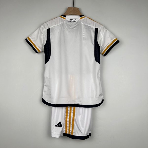 Back view of a white Adidas soccer jersey hanging on a wooden hanger, with black and gold trim and the text ¡HALA MADRID! on the upper back.