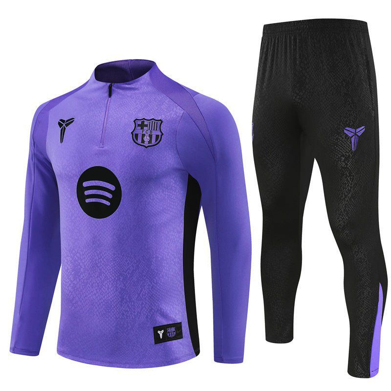 18cf6e86-bb46-491a-bdf7-28d2ca36cd4b Purple long-sleeve training jersey with a crest and Spotify logo, paired with black athletic pants on the right.