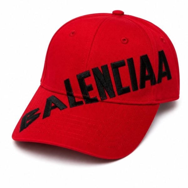 Red baseball cap with a black embroidered BALENCIAGA logo across the front, curved brim visible