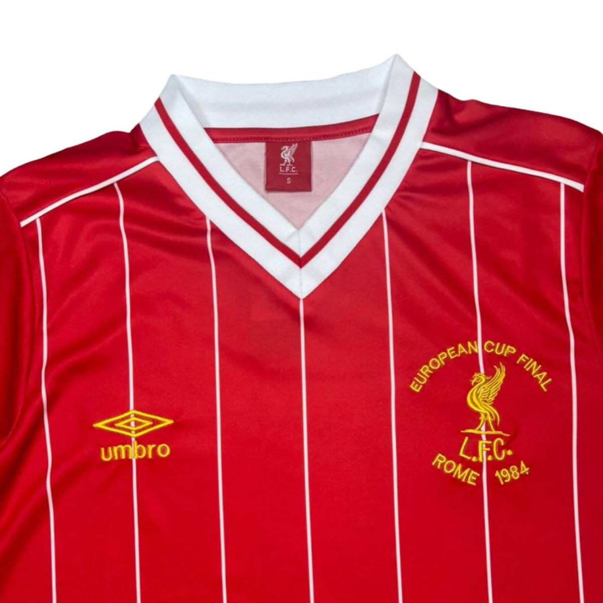 Red Liverpool FC jersey with white pinstripes, white V-neck collar, and yellow club crests: European Cup Final Rome 1984 with Umbro logo.