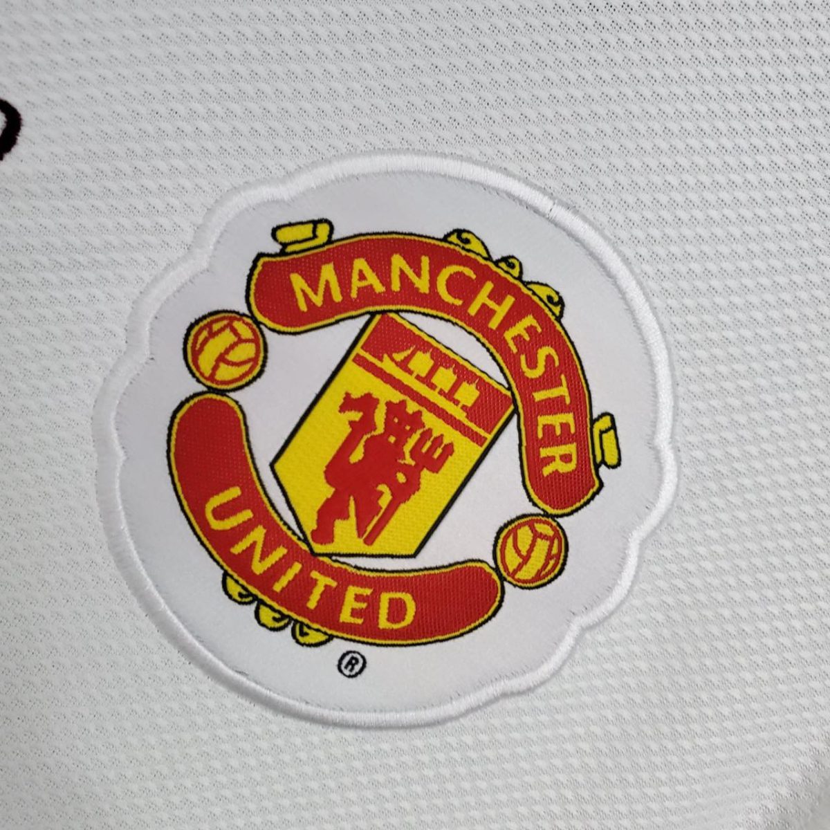 Embroidered patch of the Manchester United crest on white fabric.