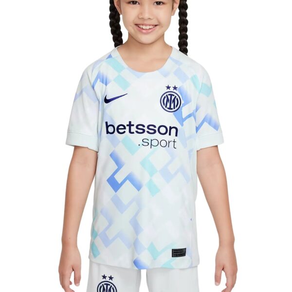 Young girl wearing an Inter Milan kids' football jersey with a geometric white-and-blue pattern, crest, and Betsson sponsor logo on the front.