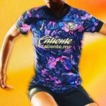 Athlete in a vibrant purple-blue-pink Caliente jersey, with the Caliente logo across the chest and a circular badge on the left chest against a yellow background.