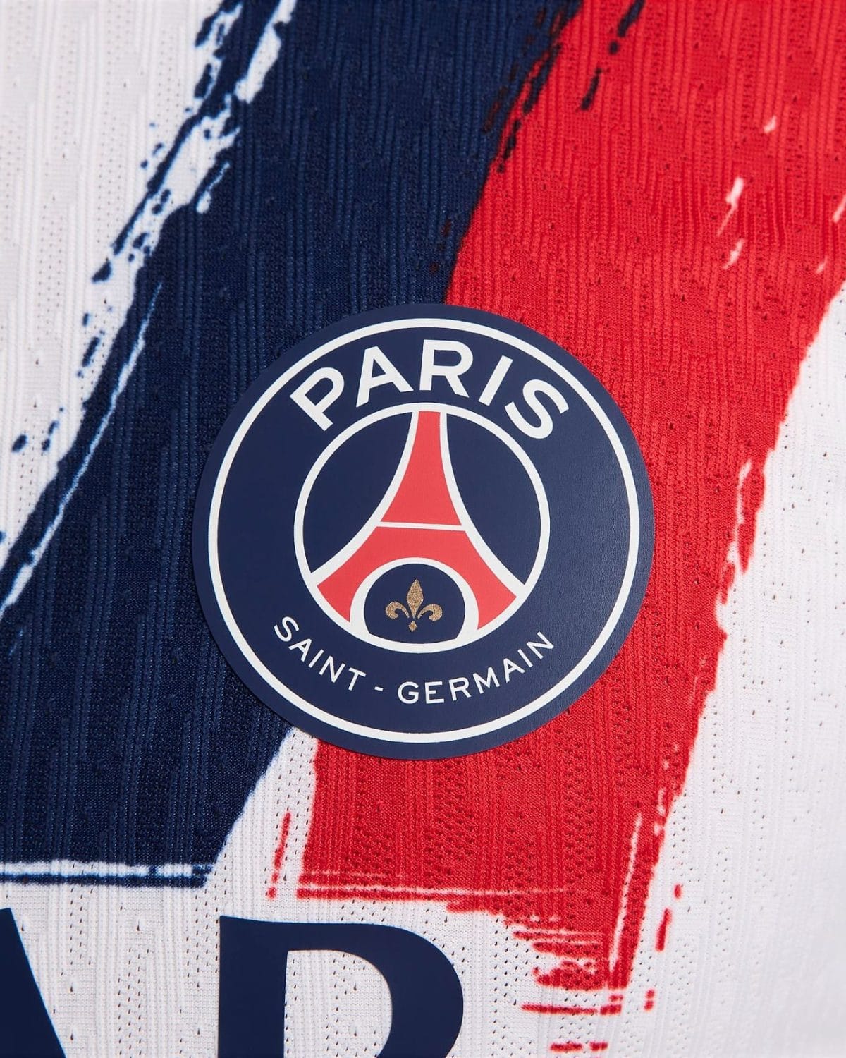 PSG crest on a blue background with red and white stripes, displayed on a textured sports jersey