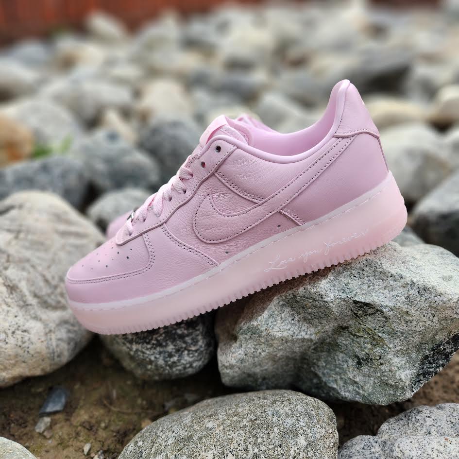 1_1080x_4e7f668f-65d6-4ab2-9ae3-e8fce58080c7 | UAE SPORT STORE Light pink Nike sneaker resting on a pile of gray rocks.