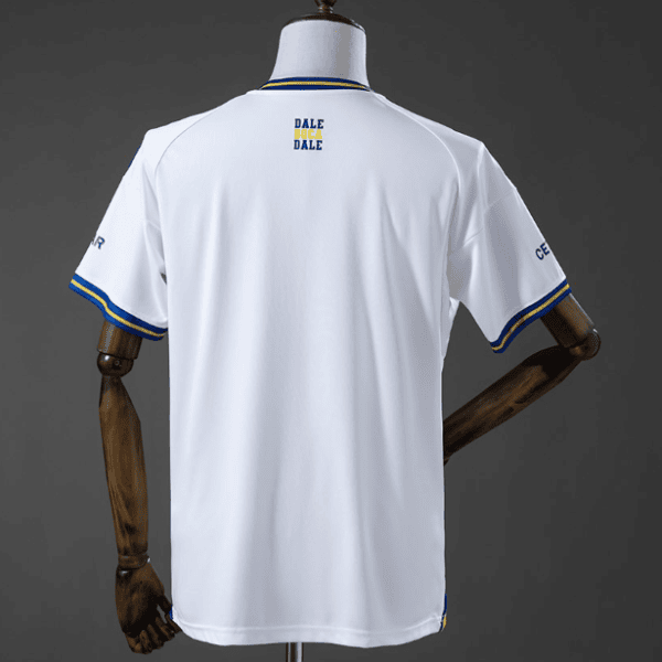Back view of a white sports jersey with blue and yellow trim, mannequin displaying small 'DALE DALE' logo on upper back and blue/yellow sleeve cuffs.