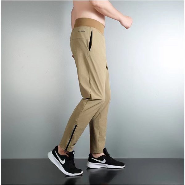 Tan cargo jogger pants with zip vents at the calves, shown in a side view paired with black Nike sneakers.