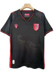 Black soccer jersey on a hanger with red trim and crest, featuring a red shield with a double-headed eagle on the chest.