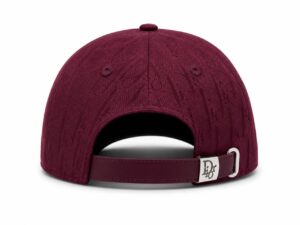 Maroon baseball cap seen from the back, with an adjustable strap and metal Dior clasp, patterned fabric all over
