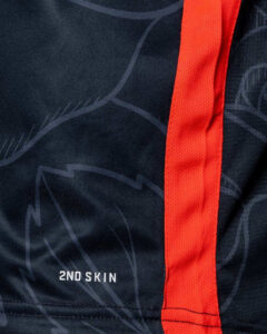 Close-up of dark blue athletic fabric with a red seam and the '2ND SKIN' logo.