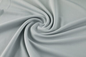 Light blue-gray fabric twisted into a smooth swirl, showcasing soft folds and texture