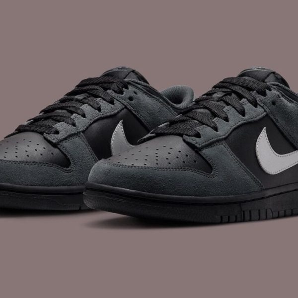 Pair of black and gray Nike sneakers with a white swoosh on a muted brown backdrop.