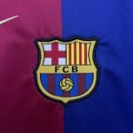 Partial FC Barcelona crest sewn on red and blue fabric backdrop, showing shield with red and yellow stripes and crest outline.