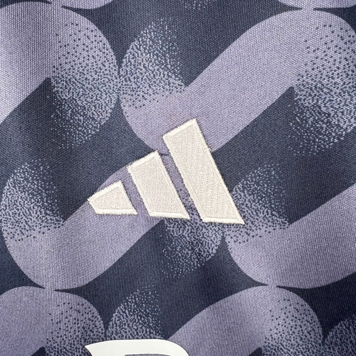 Close-up of dark blue denim fabric with a geometric chevron pattern in lighter and darker blues, and a white curved edge fragment at the bottom center.