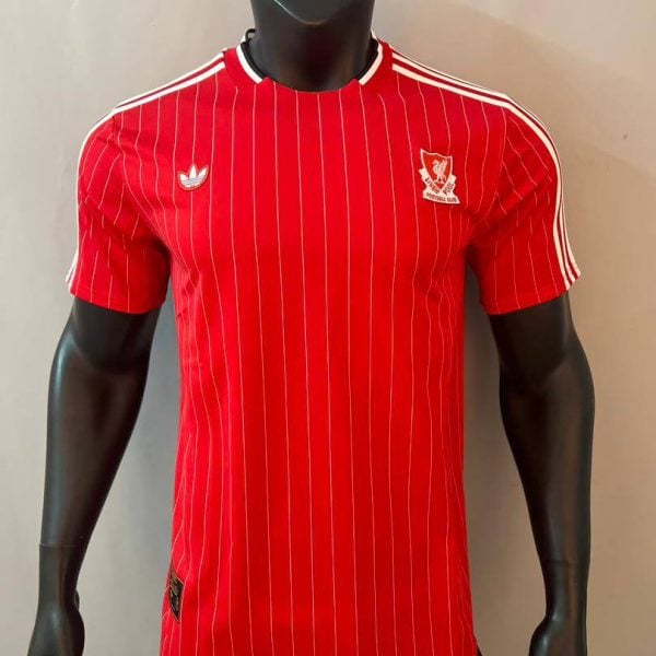 Red pinstriped Adidas football jersey with white shoulder stripes and a crest on the left chest, displayed on a black mannequin.