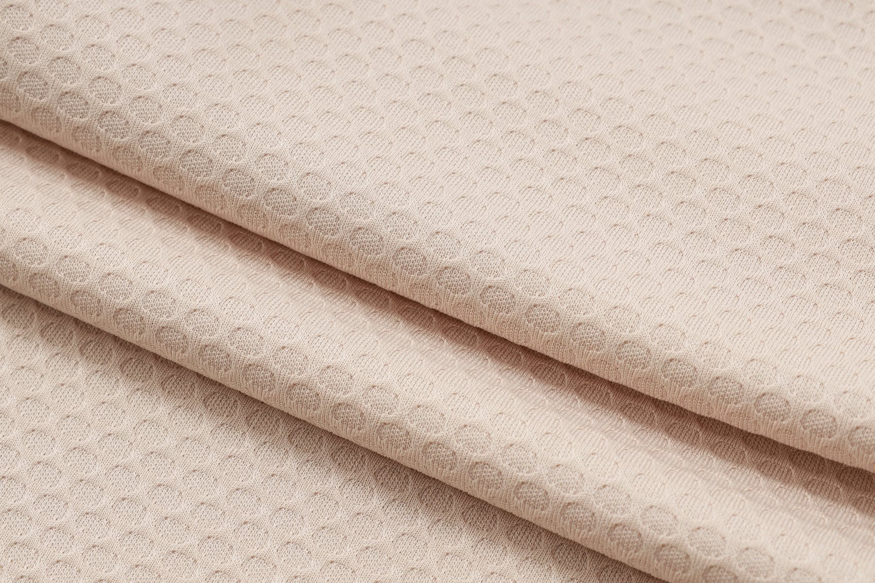 1e50d3b3 | UAE SPORT STORE Beige fabric folded with a small, repeating dotted texture pattern.