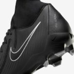 Close-up of a black Nike soccer cleat, showing the white Nike swoosh and studded sole.