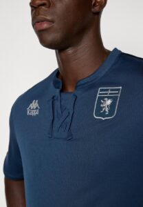 Close-up of a man wearing a blue Kappa polo with a white crest on the left chest.