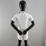 Back view of a black mannequin wearing a white shirt, arms bent with hands together in front against a gray backdrop.