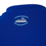 Blue polo shirt with a small light-blue embroidered crest featuring a boat and the French motto Marseille navigue par ses hauts faits near the collar on the back area.