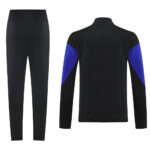 Black athletic tracksuit: straight-leg pants and a black jacket with blue sleeves on the sides. Back view shown in the image fall lines down the arms and back design.