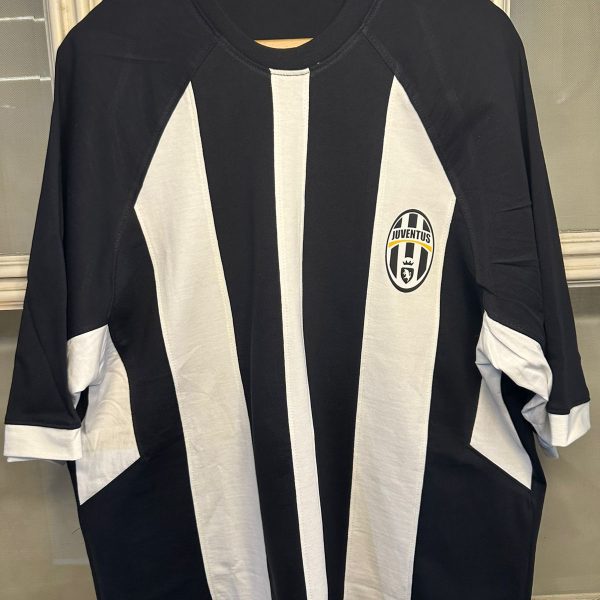 Juventus soccer jersey hanging on a wooden hanger with bold black and white vertical stripes and the team badge on the left chest area
