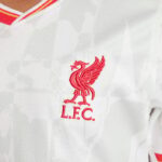 White Liverpool FC soccer jersey with red Liver Bird crest and L.F.C. initials.