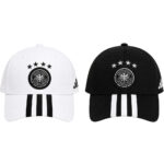 Pair of white and black baseball caps with the German Football Association crest, three stars above, and striped visors on each cap